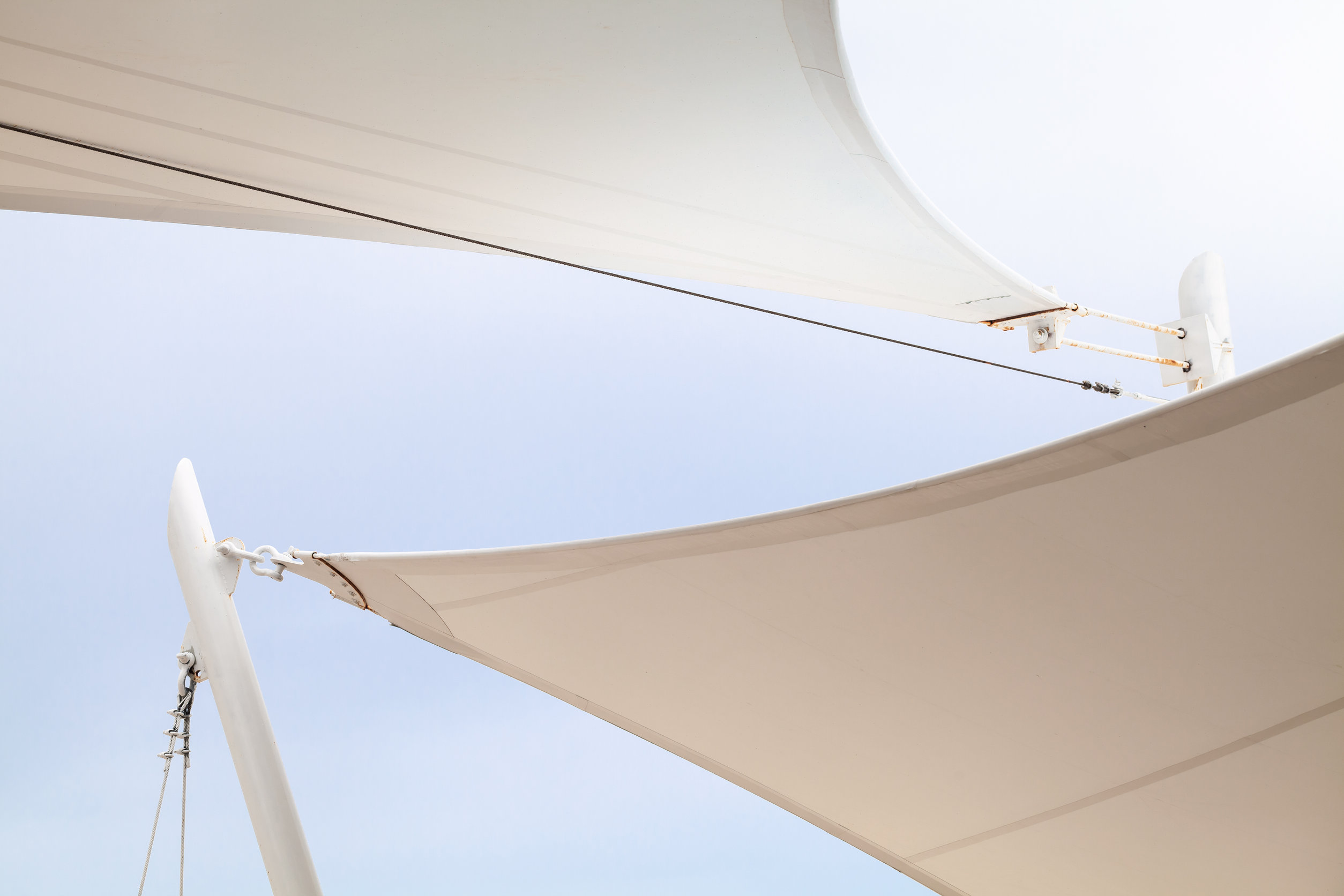 White awnings in sails shape under bright blue sky background